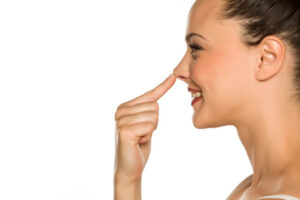 The happy, beautiful woman is touching the tip of her nose.